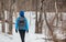 Hiker backpacking walking through the woods on snow trail path in winter. Cold weather hiking