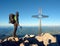 Hiker at big crucifix on mountain peak. Iron cross at Alps mountain top.