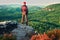 Hiker in black with red baseball cap on sharp cliff and watch to valley. Colorful summer day.