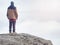 Hiker in brown red outdoor clothes watching into low clouds