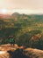 Hiker with camera on tripod takes picture from rocky summit. Alone photographer at edge photograph landscape