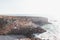 Hiker celebrates its success. Breathtaking cliffs with pebble beach in the afternoon sun on the Atlantic coast at Vila Nova de