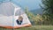 Hiker child boy resting sitting in a camping tent at mountains campsite enjoying view of summer nature.