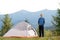 Hiker child boy standing near a tent in mountain campsite enjoying view of nature