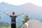 Hiker child boy standing near a tent in mountain campsite with raised hands enjoying view of nature