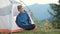 Hiker child boy stretching in a tourist tent at mountain campsite enjoying view of beautiful summer nature.