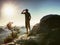 Hiker climbed up to rocky peak and enjoy view to valley bellow