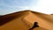 Hiker climbing to the top of the Great Sand Dune in the red dune sea of Erg Chebbi, Morocco.