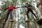 Hiker couple helping each other to cross obstacles in the forest