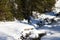 Hiker crosses snow-covered mountain river