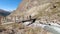 Hiker crossing a small bridge over a high mountain stream