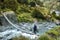 Hiker crossing Swing Bridge on the Rees Dart Track tramping in New Zealand