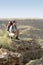 Hiker Crouching On Top Of Mountain