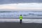 Hiker in electric windbreaker walking at sunset on a sand beach