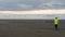 Hiker in electric windbreaker walking at sunset on a sand beach