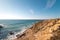 Hiker enjoys the breathtaking cliffs with a pebble beach in the afternoon sun on the Atlantic coast at Vila Nova de Milfontes,
