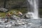 Hiker Extending Arm To Friend Under Waterfall