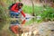 Hiker filling canteen of raw water in a creek.