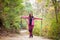 Hiker girl standing on a wide trail in the mountains. Backpacker with pink jacket in a forest. Healthy fitness lifestyle outdoors