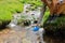 Hiker hand filling canteen of raw water in a creek