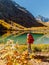 Hiker happy woman on crystal lake in autumnal mountains