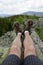 Hiker with hiking shoes, boots and footwear is sitting on the rock