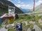 Hiker holding beer glass with foot in rubber clogs relaxing at view from Nurnberger Hutte hut, valley with mountain