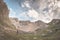 Hiker holding mug and relaxing in alpine valley with lake. Summer adventures and exploration on the Alps. Dramatic sky, toned