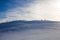 Hiker  with long shadow on top of Mount Ciucas peak on a sunny winter day at sunset