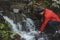 Hiker on a long trail refills drinking water from a mountain spring into a glass container. Replenishing clean water for cooking