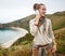 Hiker looking aside and using mobile phone in front of ocean