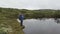 A hiker is looking at a small pond.