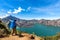 Hiker man with backpack spreading hand, enjoy and happy with active volcano Baru Jari, Lake Segara Anak and summit of Rinjani moun