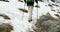 Hiker man with backpack walking on snowy trail path.Following behind legs detail.Real backpacker people adult hiking or