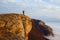 Hiker man cheering with arms spread and raised to the sky after hiking mountain top summit. Climber with backpack on the