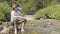 Hiker man drinking spring water from bottle on river shore in mountain forest