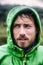 Hiker man on extreme hike adventure outdoor raining wearing waterproof rain jacket hood. Portrait of rugged scandinavian