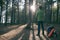 Hiker man in felt hat with backpack and Ñamping gear standing in pine woods at sunset. Adventure, trekking, local travel. Copy