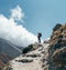 Hiker man silhouette on clouds background standing on path going over the Imja Khola valley and enjoying mountain views during an