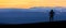 Hiker man silhouette standing at spectacular blue layered mountain ranges silhouettes. Sunset landscape in Iceland.