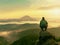 Hiker man take a rest on mountain peak. Man sit on sharp summit and enjoy spectacular view.