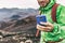 Hiker man taking photo with phone holding blue cover smartphone during outdoor activity in nature landscape. Hiking