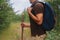 Hiker man walking with a wooden stick in forest