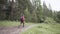 Hiker man wearing hiking backpack and red jacket while walking in summer forest. Stock footage. Young man following the