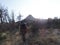 Hiker with military camo clothes and climbing equipment walks up on a hill.