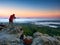 Hiker and photographer stay with tripod on cliff and takes photos. Autumn windy landscape,