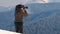 Hiker photographer taking pictures of snowy nature in winter mountains.