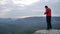 Hiker in pink sportswear on rocky view point and taking photos of misty morning landscape. Hike in rocks.