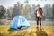 Hiker posing by a pond next to a blue tent