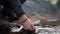 A hiker puts his hand down into a cold river.